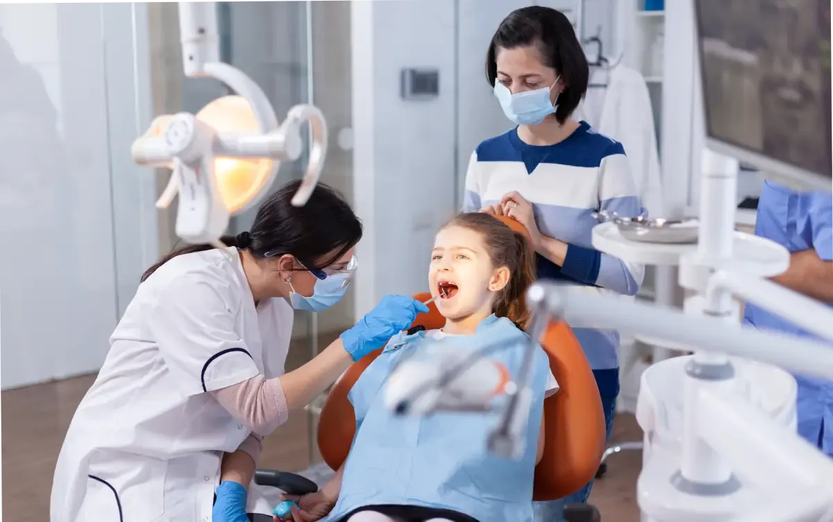 A dentist examining a young girl’s teeth