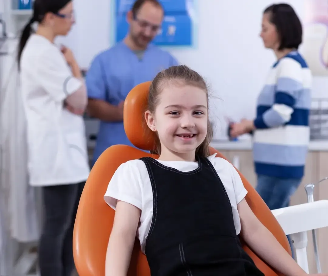 Smiling child in a dental chair with the Skyview Dental team